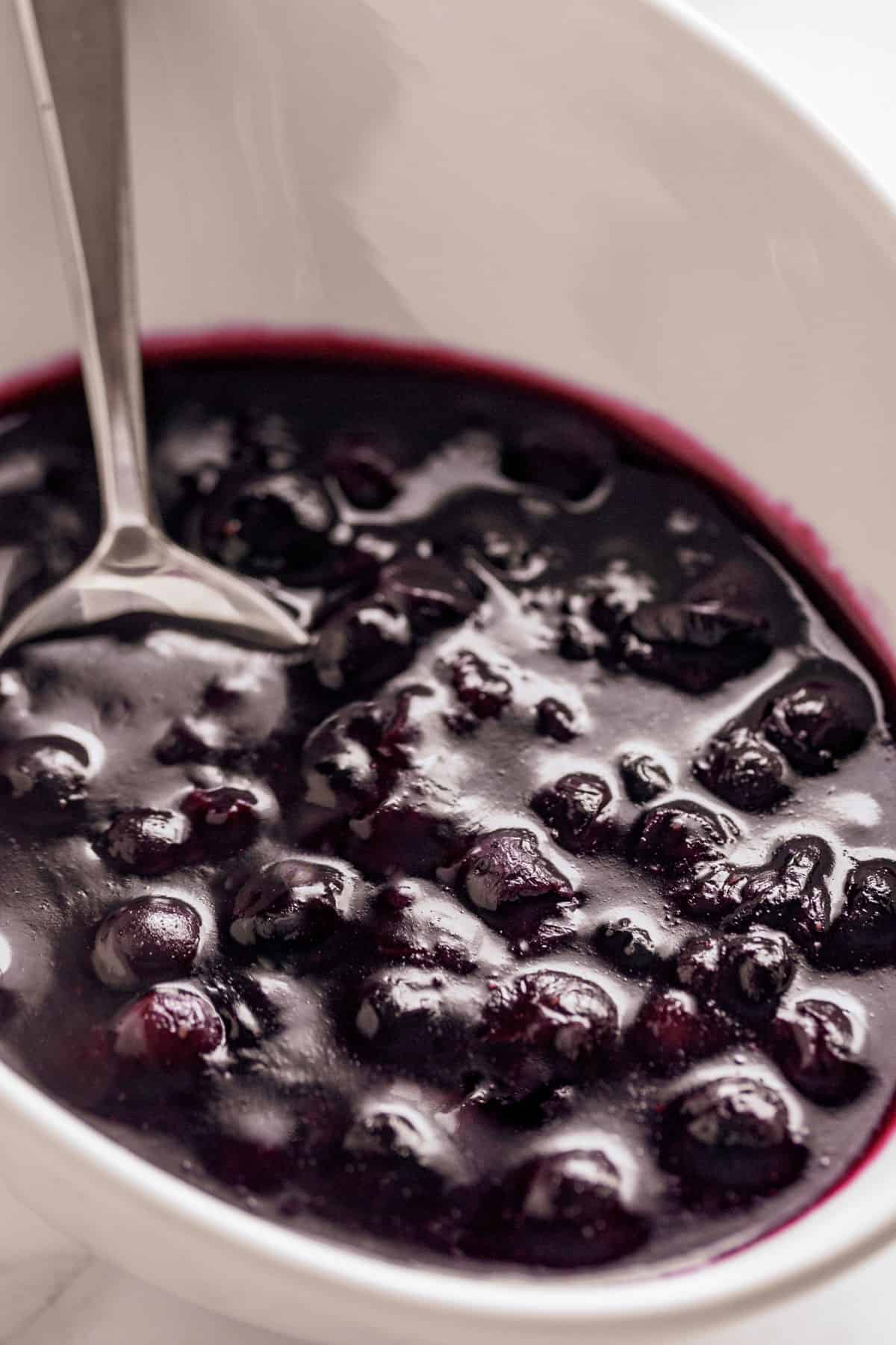 Blueberry Sauce served in a white bowl with a metal spoon | craveitall.com