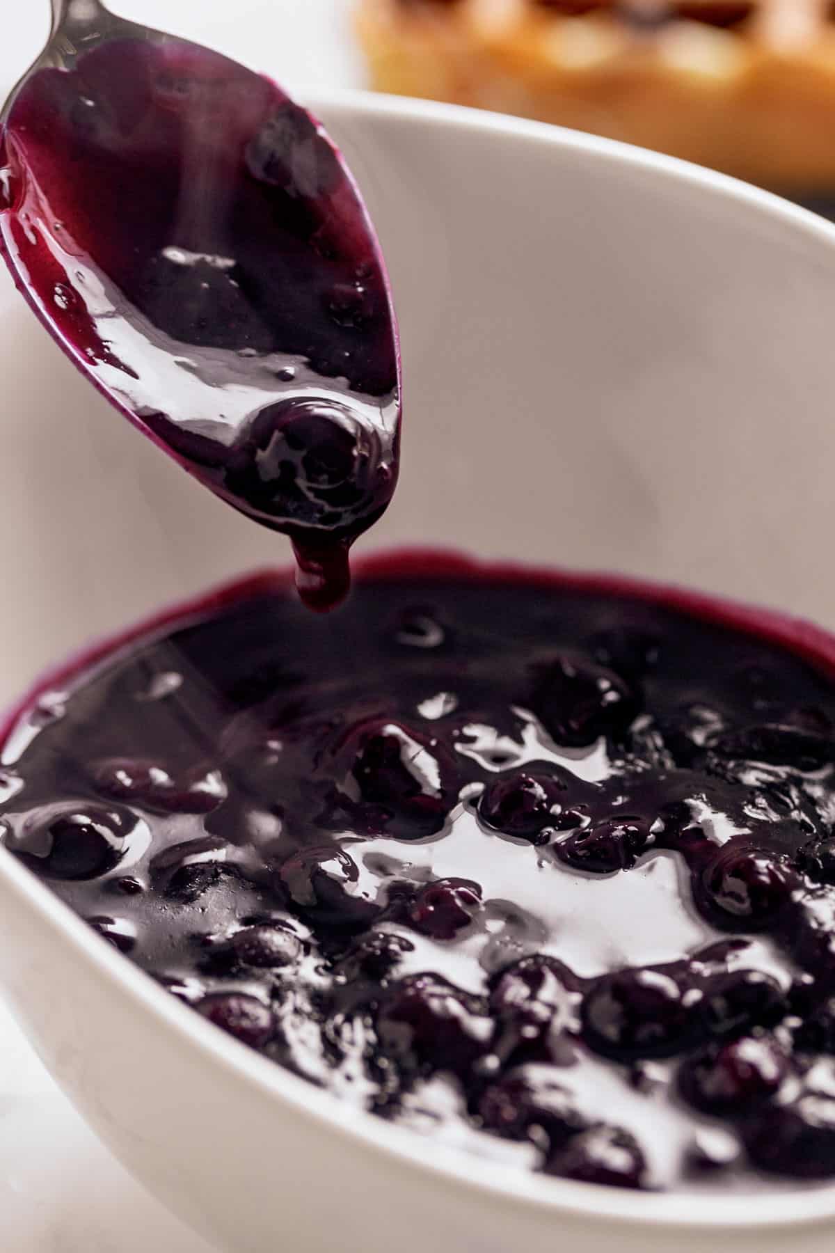 Blueberry Sauce served in a white bowl with a metal spoon | craveitall.com