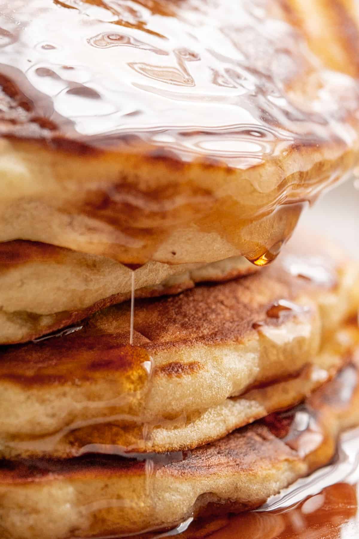 Easy Fluffy Pancakes close up image drizzled with maple syrup | craveitall.com