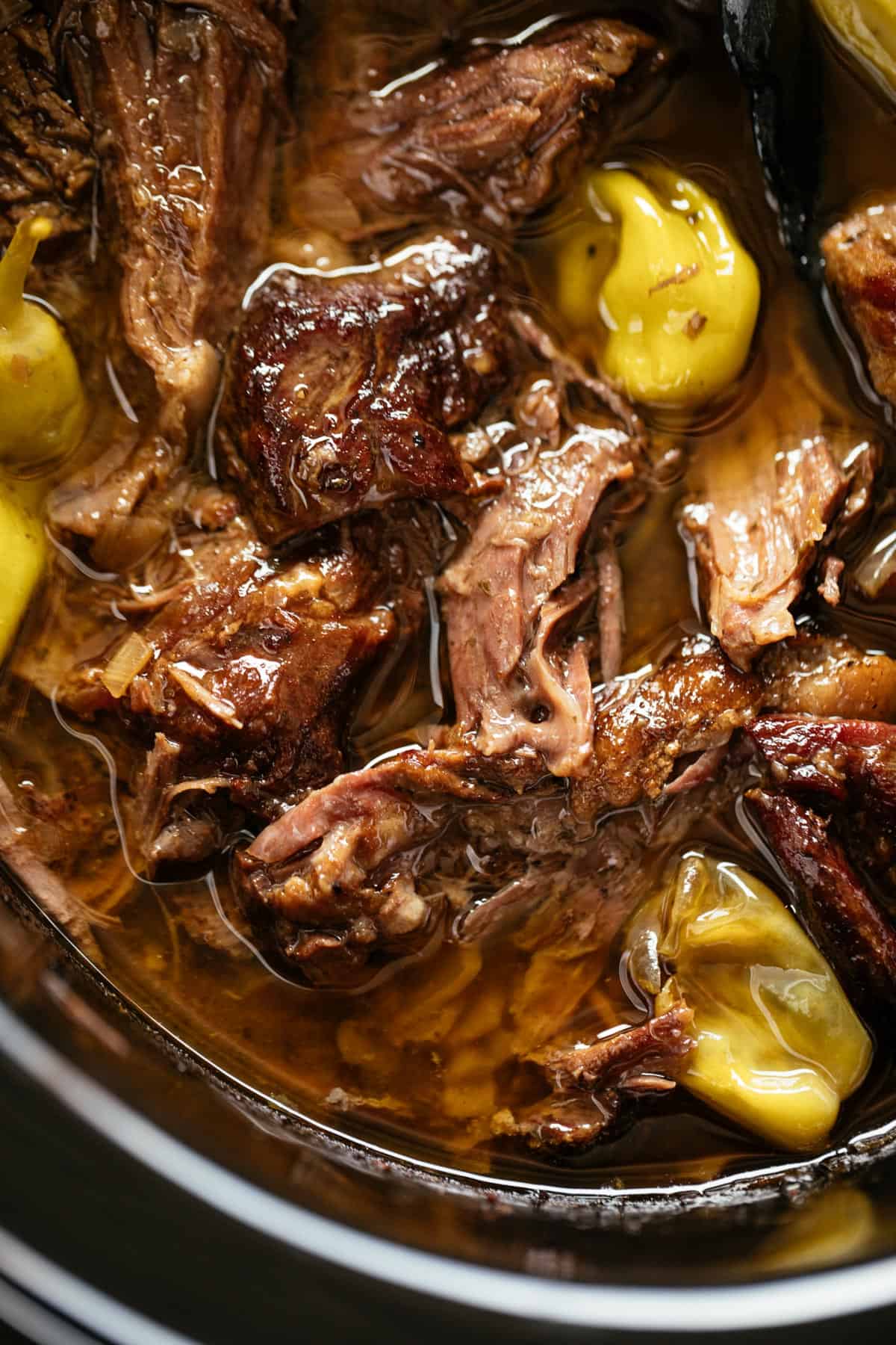 Mississippi Pot Roast cooked low and slow in a black slow cooker bowl. | craveitall.com