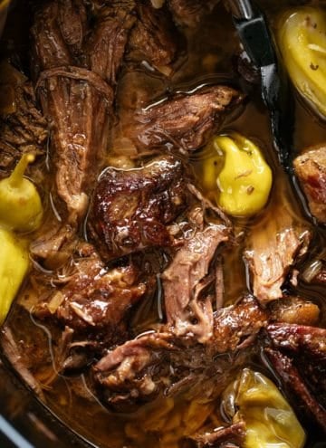 Mississippi Pot Roast cooked low and slow in a black slow cooker bowl. | craveitall.com