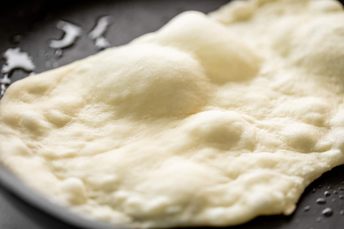 Naan bread cooked in a skillet on high heat | craveitall.com